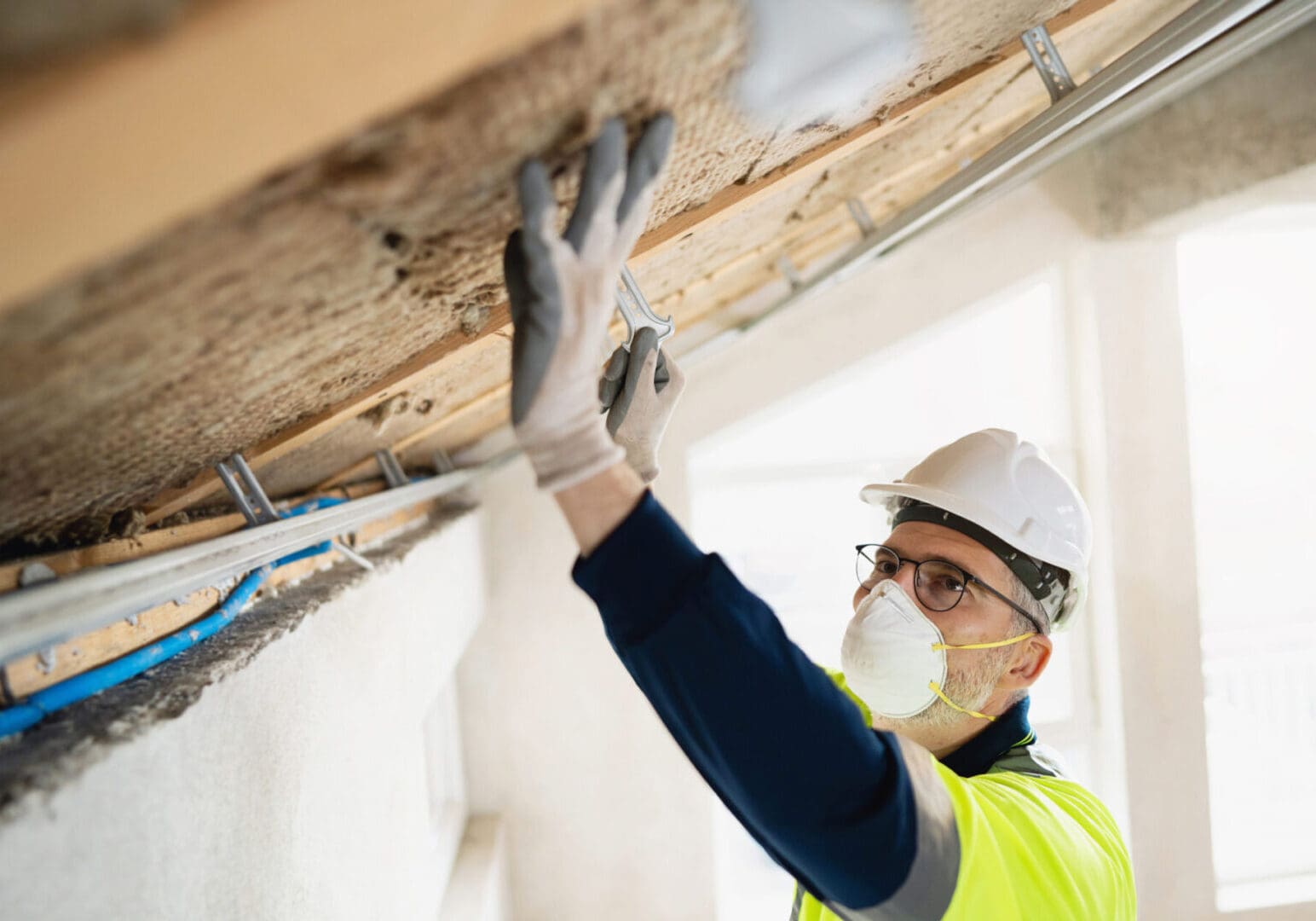 Construction worker sanding a wooden beam indoors.